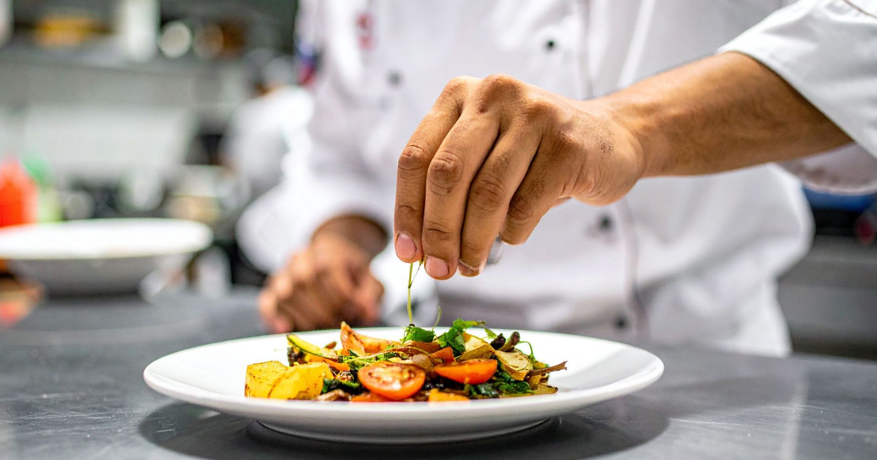 A chef plating a dish in a hospitality kitchen