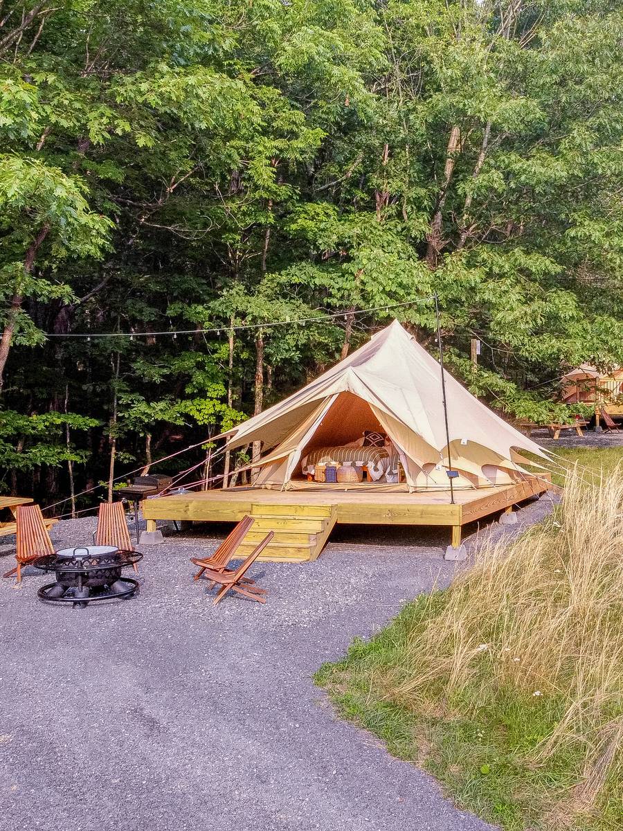 A furnished canvas bell tent on a timber deck at Firefly Ridge, with fire pit and chairs